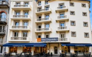 a building with tables and chairs in front of it at Hôtel Compostelle in Lourdes