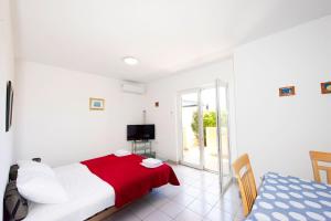 a white bedroom with a bed and a television at Apartments Silvia in Novalja