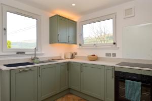 a kitchen with green cabinets and two windows at Kilbride Lodge in Carrick