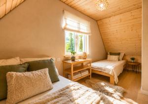 a bedroom with a bed and a window and a chair at Domki nad Zaporą w centrum Soliny przy Zaporze - wybrane domki z jacuzzi in Solina