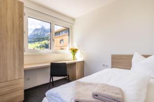 a bedroom with a bed and a desk with a window at Haus Gaues in Dalaas