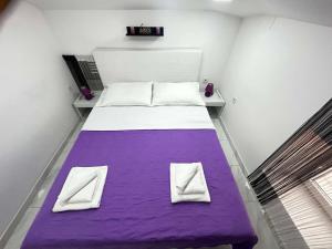 a large bed with purple sheets and white pillows at Apartment Decumana in Krk
