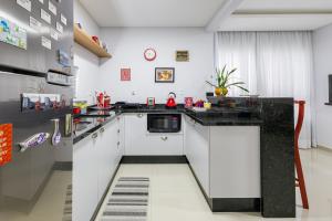 a kitchen with white cabinets and a black counter top at Little Britain no centro de Pomerode in Pomerode +27 photos