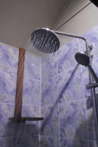 a shower with a shower head in a bathroom at Fortunate Lodge, Restaurant & Bar in Lénakel