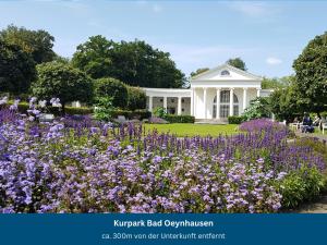 a garden with purple flowers in front of a white house at Bad Oeynhausen - City, Küche, Netflix, Wifi, zentral, StudioApartment in Bad Oeynhausen