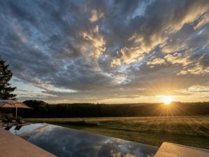 a sunset over a swimming pool with the sun setting at Schwarzwald Chalet Auwald in Freiamt