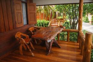 a wooden table and chairs on the porch of a house at Lay de Bua Resort in Phatthalung