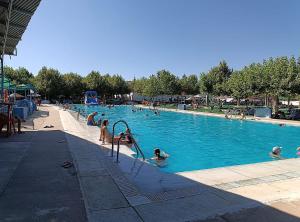 a group of people in a swimming pool at LAS CABAÑAS DEL LAGO más pase piscina las 2 columnas Del 1 junio 2026 al 30 agosto 2026 in Córdoba