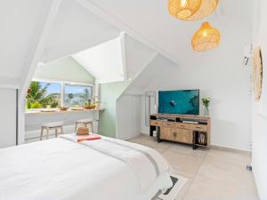 a white bedroom with a bed and a tv at Shell Beach - Magnifique Loft sur la plage in Baie Nettle