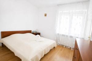 a white bedroom with a bed and a window at Extra Apartamenty - Apartament przy plaży in Sopot