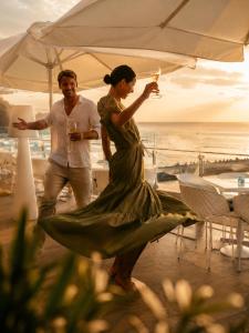 a man and a woman standing under an umbrella holding wine glasses at HVD Nympha Hotel - All Inclusive, Private Beach & Free Parking - Adults Only in Golden Sands +46 photos