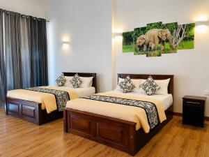 two beds in a room with two elephants painting on the wall at Bundala Forest Resort Yala in Weerawila +15 photos