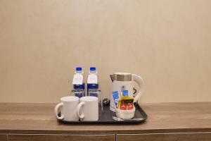 a tray with cups and bottles of water on a counter at RT Serene Hotel - Hyderabad in Hyderabad