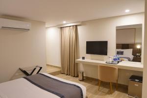 a hotel room with a bed and a desk with a television at RT Serene Hotel - Hyderabad in Hyderabad