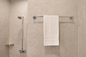 a bathroom with a shower with a white towel at RT Serene Hotel - Hyderabad in Hyderabad +55 photos