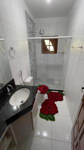 a bathroom with a sink and red roses on the floor at Casa Ferrari in Santa Teresa