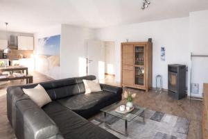 a living room with a black leather couch and a table at Ferienwohnung Achterbrise mit Kamin in Zinnowitz
