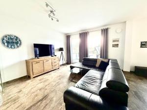 a living room with a leather couch and a tv at Ferienwohnung Achterbrise mit Kamin in Zinnowitz +29 photos