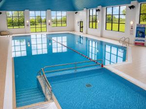 a large swimming pool with blue water in a building at The Wiltshire Hotel, Golf and Leisure Resort in Swindon