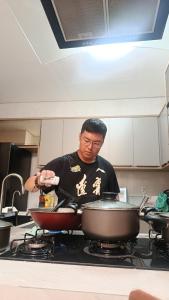 a man cooking food in a pan on a stove at Suite Vila dos Cabanos Barcarena in Barcarena +4 photos