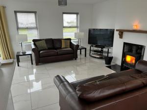 a living room with couches and a tv and a fireplace at Beach House in Donegal