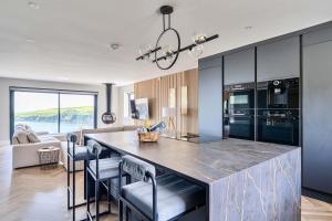 a kitchen with a large kitchen island with chairs at Seaglass Point in Mevagissey
