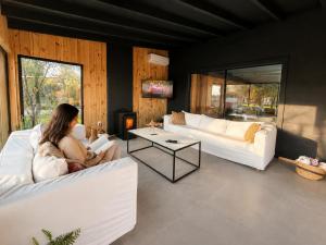 a woman sitting on a couch in a living room at La Bonita Suites Punta Colorada in Punta Colorada
