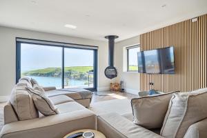 a living room with couches and a flat screen tv at Seaglass Point in Mevagissey