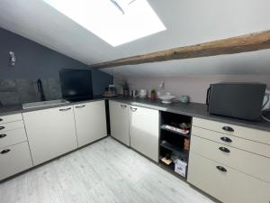 a kitchen with white cabinets and a skylight at Les Vieux Platanes Loft chaleureux in La Crau