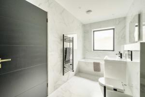 a white bathroom with a sink and a bath tub at Seaglass Point in Mevagissey +53 photos
