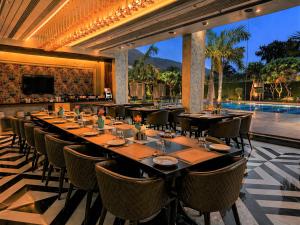 a dining room with tables and chairs and a pool at Hillcrest Hotel & Resort, Abu Road in Ābu Road