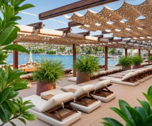 a deck with chaise lounges and chairs on the water at Mare Deluxe Residences & Villas in Bodrum City