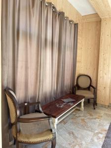 a room with a wooden table and a curtain at Infinity Snowline , Kalga in Kalgha