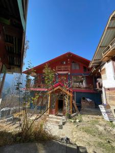 a red building with a balcony in front of it at Infinity Snowline , Kalga in Kalgha