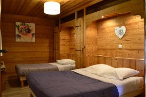 two beds in a room with wooden walls at Chalet Fleur des Alpes 1 in Les Gets