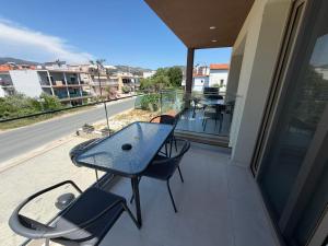 a table and chairs on a balcony with a view of a street at Elegant Corner Superior Rooms & Apartments in Limenaria