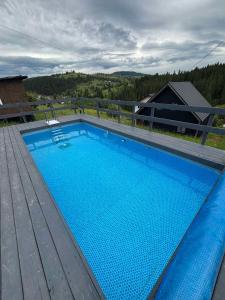 a large blue swimming pool on a wooden deck at Котедж HOLIDAY HOUSE in Yablunytsya