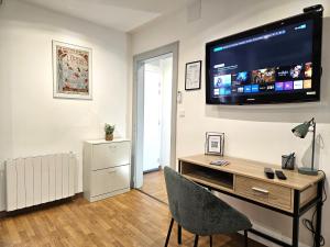 a living room with a desk with a television on a wall at Cosy room - centre ville - 2 pers in Sarreguemines