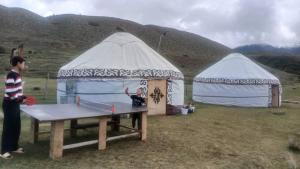 a man standing in front of two tents with a table tennis at Актан yurt cemp in Chong-Kyzylsu +8 photos