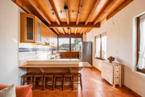 a kitchen with wooden ceilings and a kitchen island with stools at Llanes Casa cerca Playa y Centro – Encina Pancar in Pancar