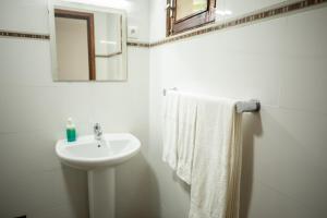 un bagno bianco con lavandino e specchio di Refúgio Da Ilha a Rio do Ouro Altre 13 foto