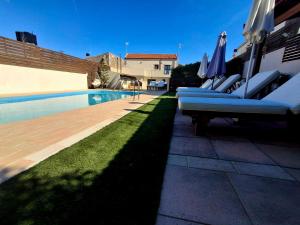 a pool with lounge chairs and umbrellas next to a building at Villa Thalasena in episkopi-heraklion