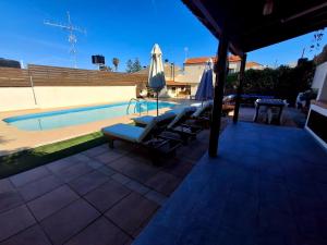 a swimming pool with lounge chairs and an umbrella at Villa Thalasena in episkopi-heraklion