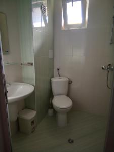 a bathroom with a toilet and a sink and a window at Family Hotel PUDEV in Sunny Beach