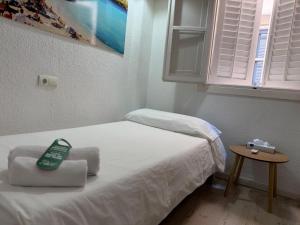 a small bedroom with a white bed with a window at Hostal Ibiza in Ibiza Town +14 photos