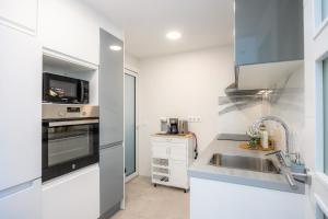 a white kitchen with a sink and a microwave at Apartamento Lliteras 2C Ref 9003 in Cala Millor