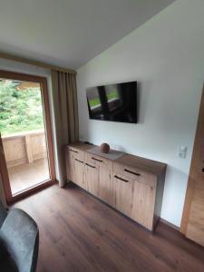 a room with a tv on a wall with a wooden cabinet at Appartement Schroll in Schwendau