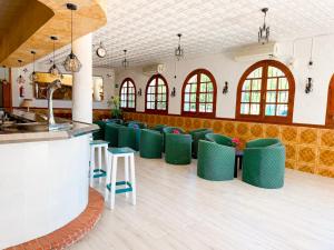 a large room with green chairs and a bar at Hostal Los Arcos Vejer in Vejer de la Frontera