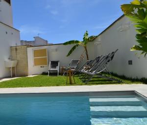 a pool with chairs and a table next to a house at Carpentry in Uggiano la Chiesa