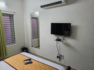 a room with a bed with a flat screen tv on the wall at GT Homestay in Chennai